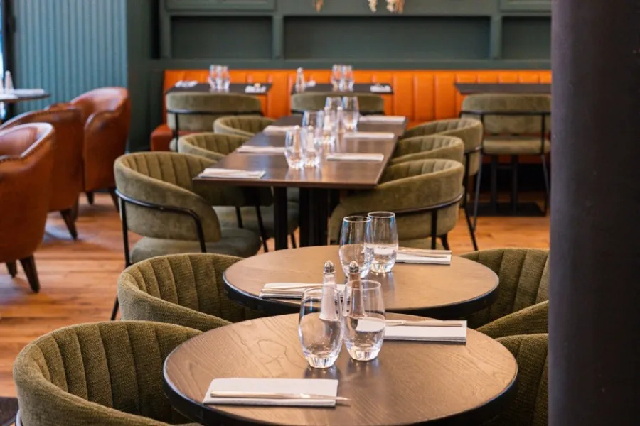 La salle du Bistrot Jad, fauteuils cuir cognac et verrière fleurie